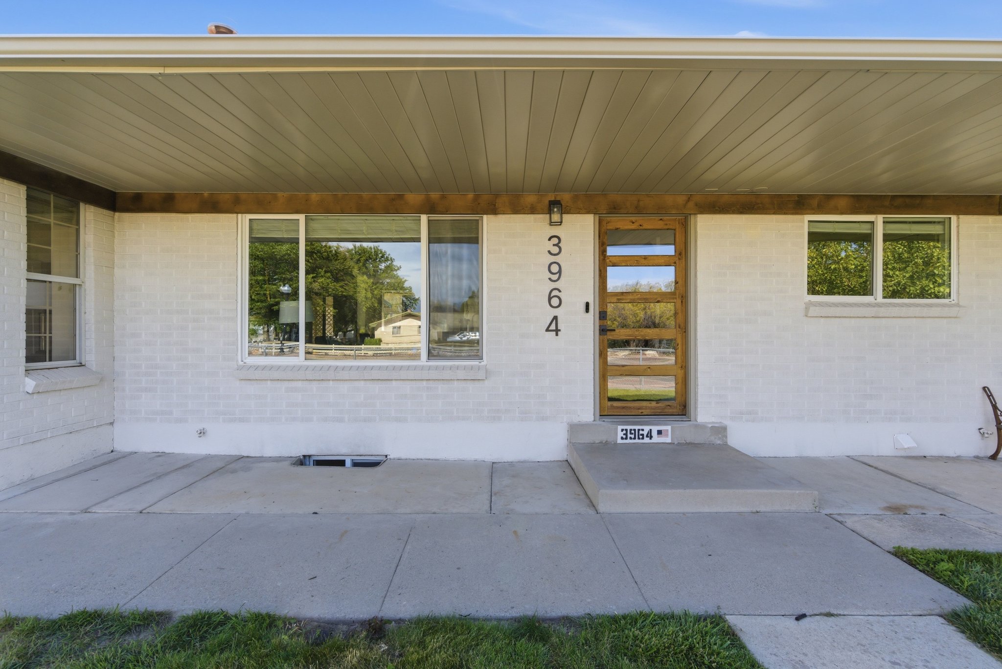 White painted brick exterior featuring a contemporary wood-finish entry door with multiple glass inserts