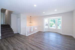 Spacious living area featuring wood-finish flooring, a bay window, recessed lighting, and a contemporary chandelier
