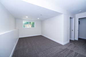 Spacious room featuring neutral carpeting, recessed lighting, and a window providing natural illumination