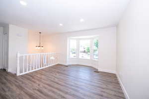 Spacious interior with wood-finish flooring, a bay window, recessed lighting, and a modern chandelier