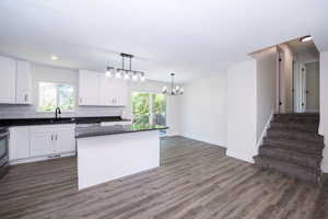 Contemporary kitchen featuring white cabinetry, dark countertops, a subway tile backsplash, stainless steel appliances, and a central island