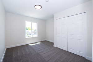 Spacious room featuring neutral paint, gray carpet, a white framed window, and bi-fold closet doors