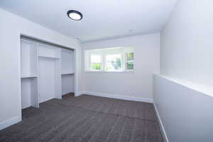 Room featuring textured gray carpeting, a built-in closet with shelving, a recessed window, white walls, and a contemporary flush-mount ceiling light fixture