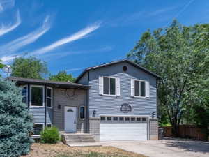Split-level residence featuring blue siding, a two-car garage with a white door, and a gray brick facade