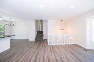 Open-concept living area featuring wood-finish flooring, recessed lighting, and a modern black chandelier