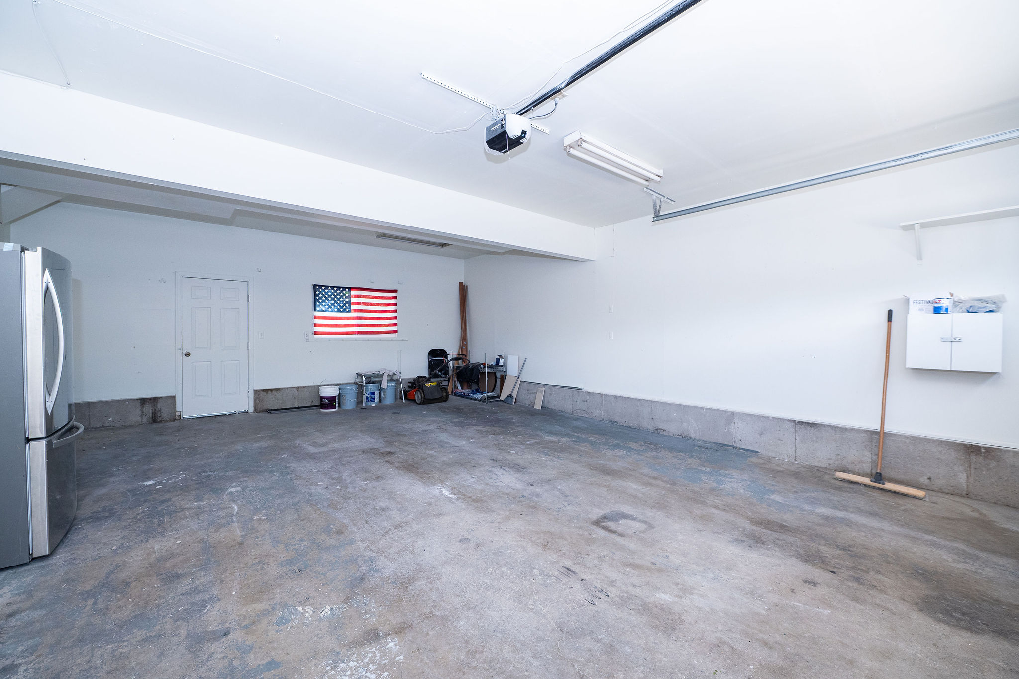 Spacious garage featuring a concrete floor, painted white walls, and an overhead garage door opener