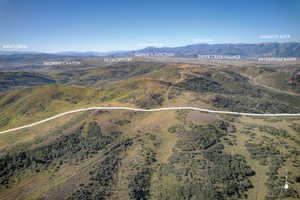 Expansive mountain landscape featuring broad valleys, distant peaks, and a clear sky