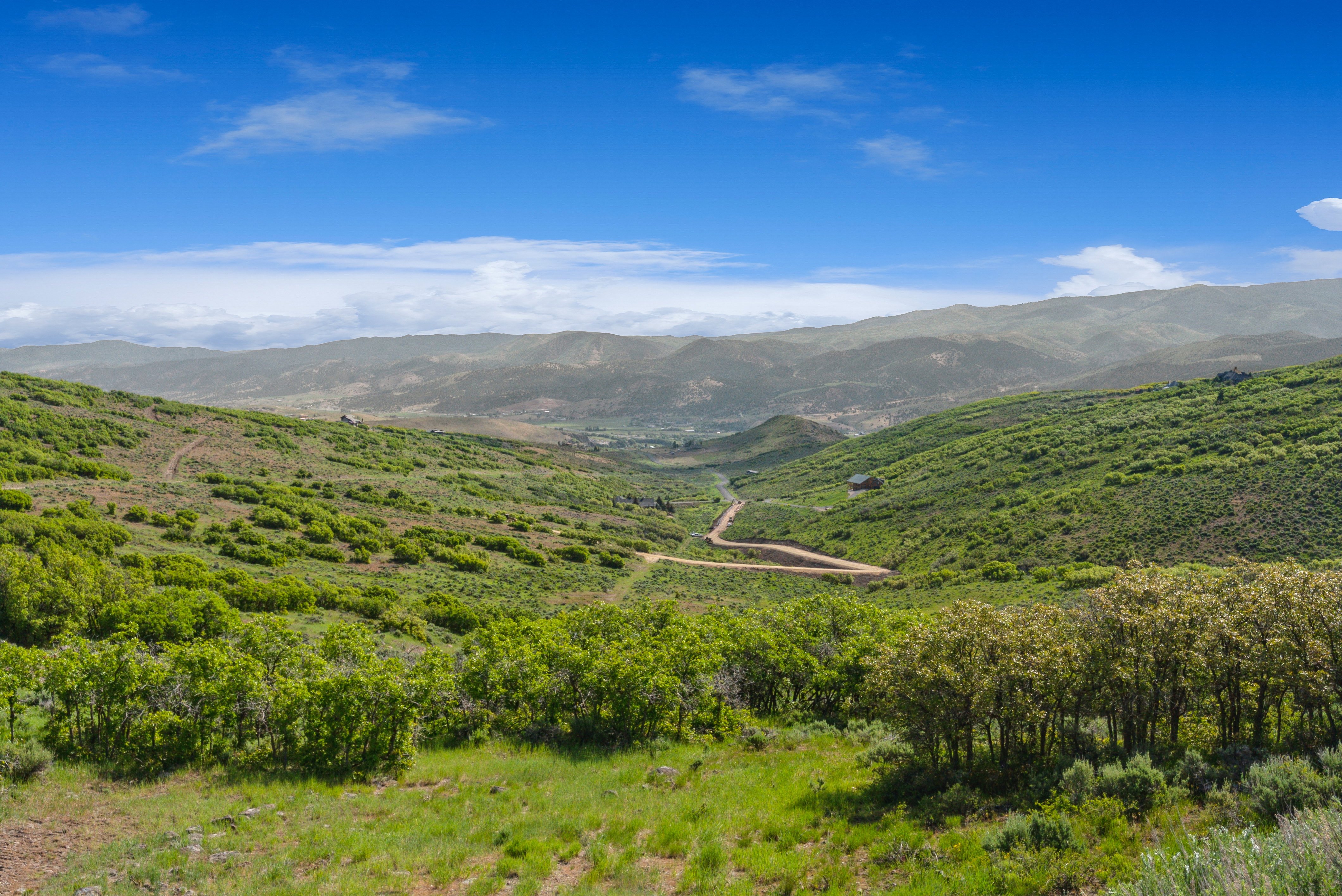 Expansive mountain landscape featuring rolling green hills and a clear blue sky