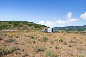 Expansive open terrain featuring natural vegetation, distant mountains, and a clear sky