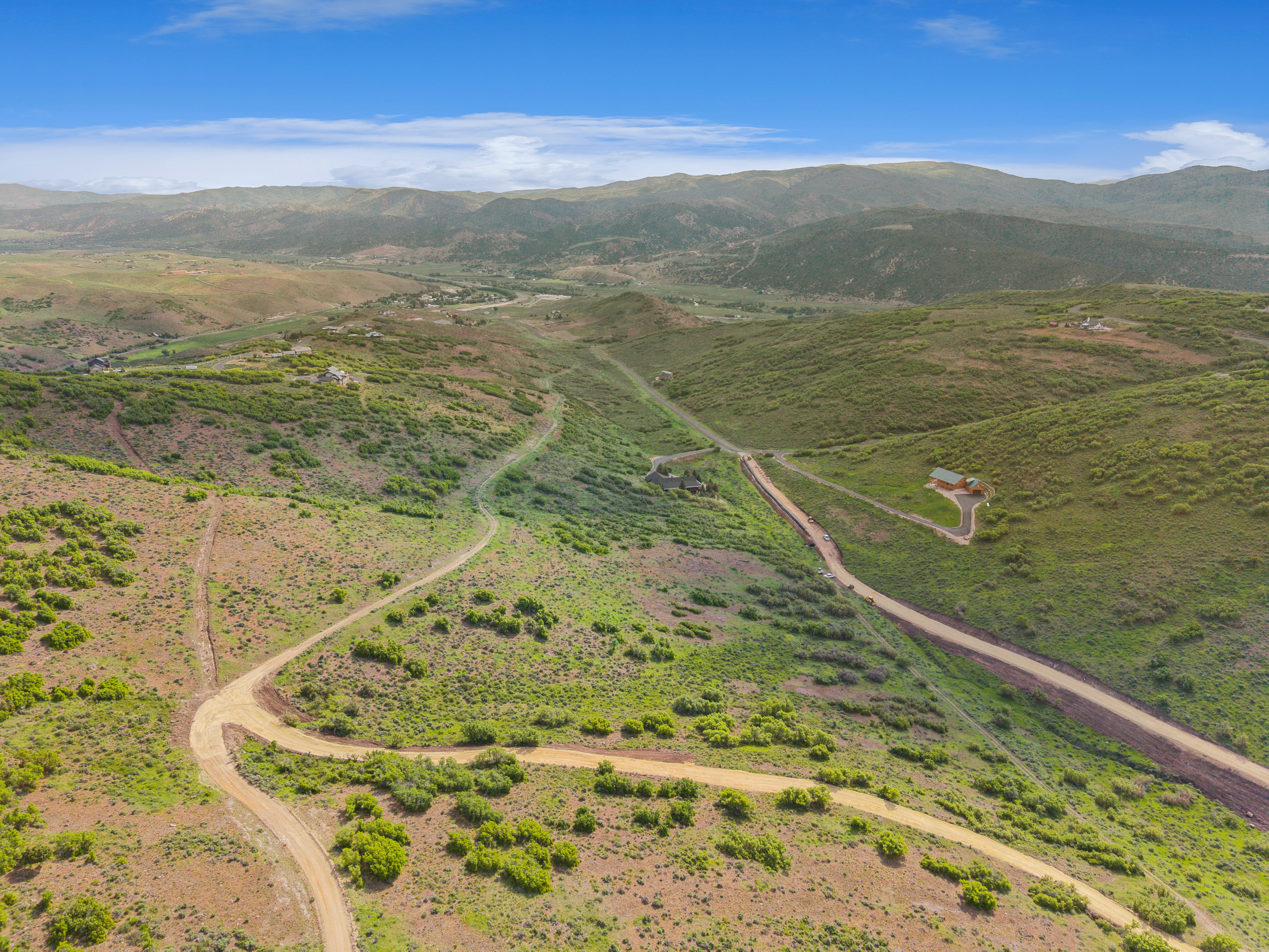 Expansive rural landscape featuring rolling hills and distant mountains under a clear blue sky