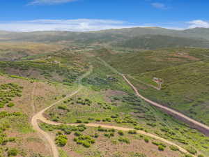 Expansive rural landscape featuring rolling hills and distant mountains under a clear blue sky