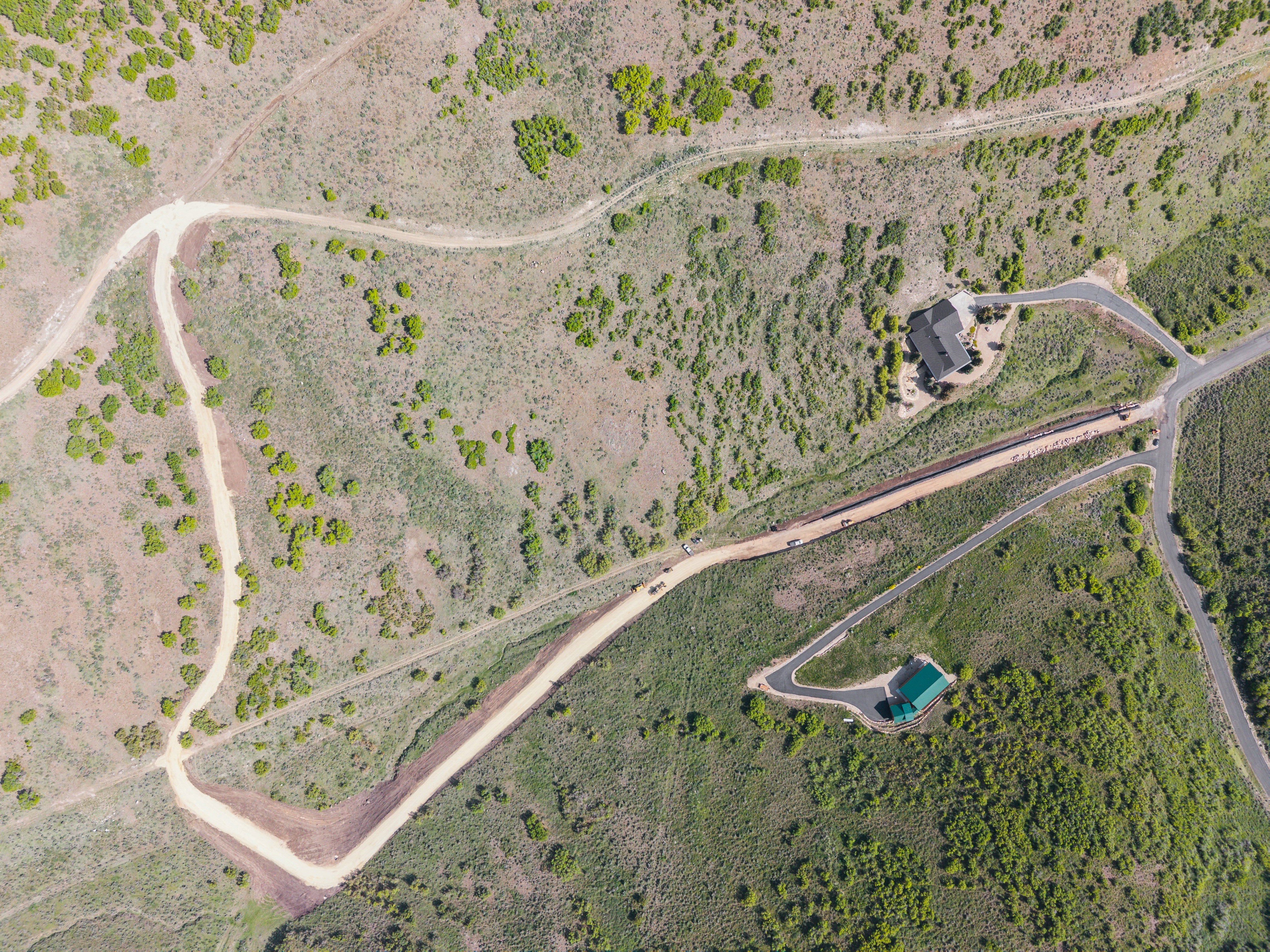 Expansive aerial property featuring two distinct structures with driveways and surrounding natural terrain