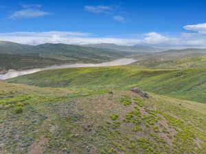 Expansive natural landscape featuring rolling green hills and a prominent body of water