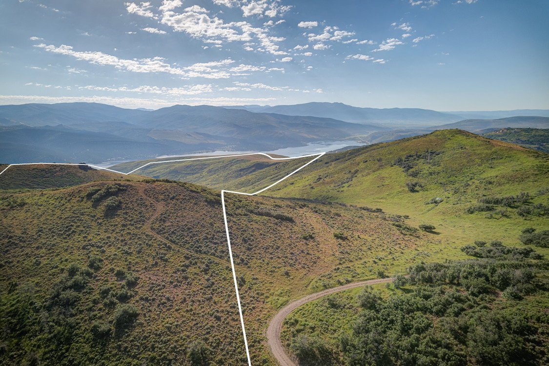 Expansive mountain property featuring rolling hills and distant water