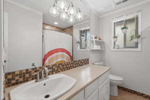 Bathroom featuring a vanity with a white basin sink, brushed nickel faucet, and a tiled backsplash
