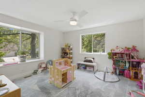 Spacious room featuring multiple large windows, recessed lighting, a ceiling fan, light-toned walls, and patterned carpeting
