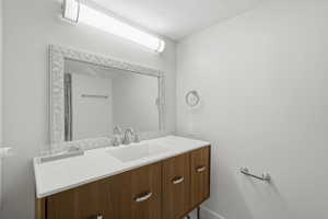 Vanity area featuring a wood-finish cabinet with double sinks, light-toned countertop, and an ornate framed mirror
