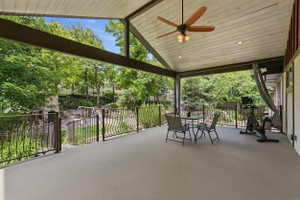 Spacious covered patio featuring a vaulted wood-finish ceiling, ceiling fan, recessed lighting, and ornate metal railings