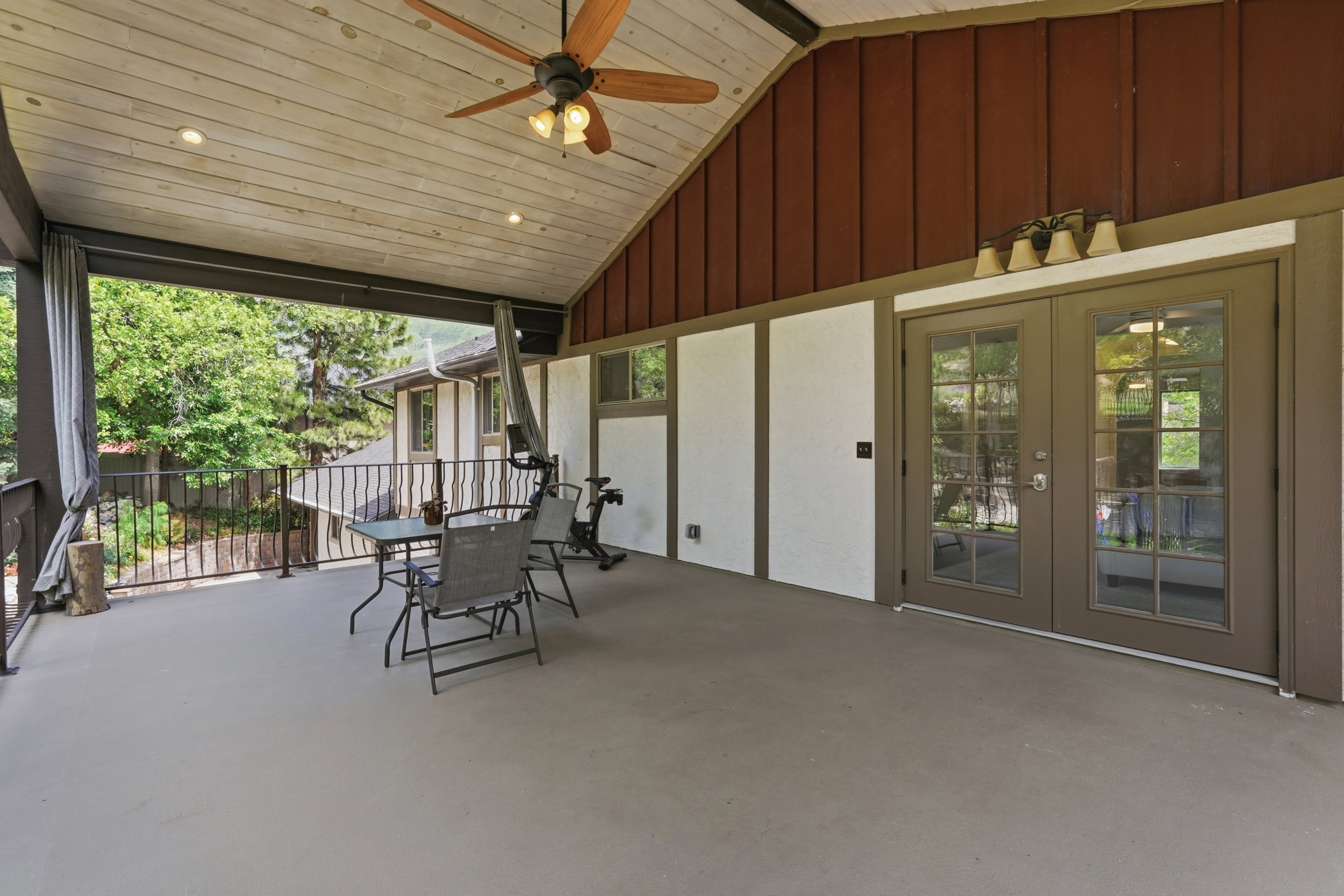 Covered outdoor deck with a vaulted wood-finish ceiling, recessed lighting, and a ceiling fan