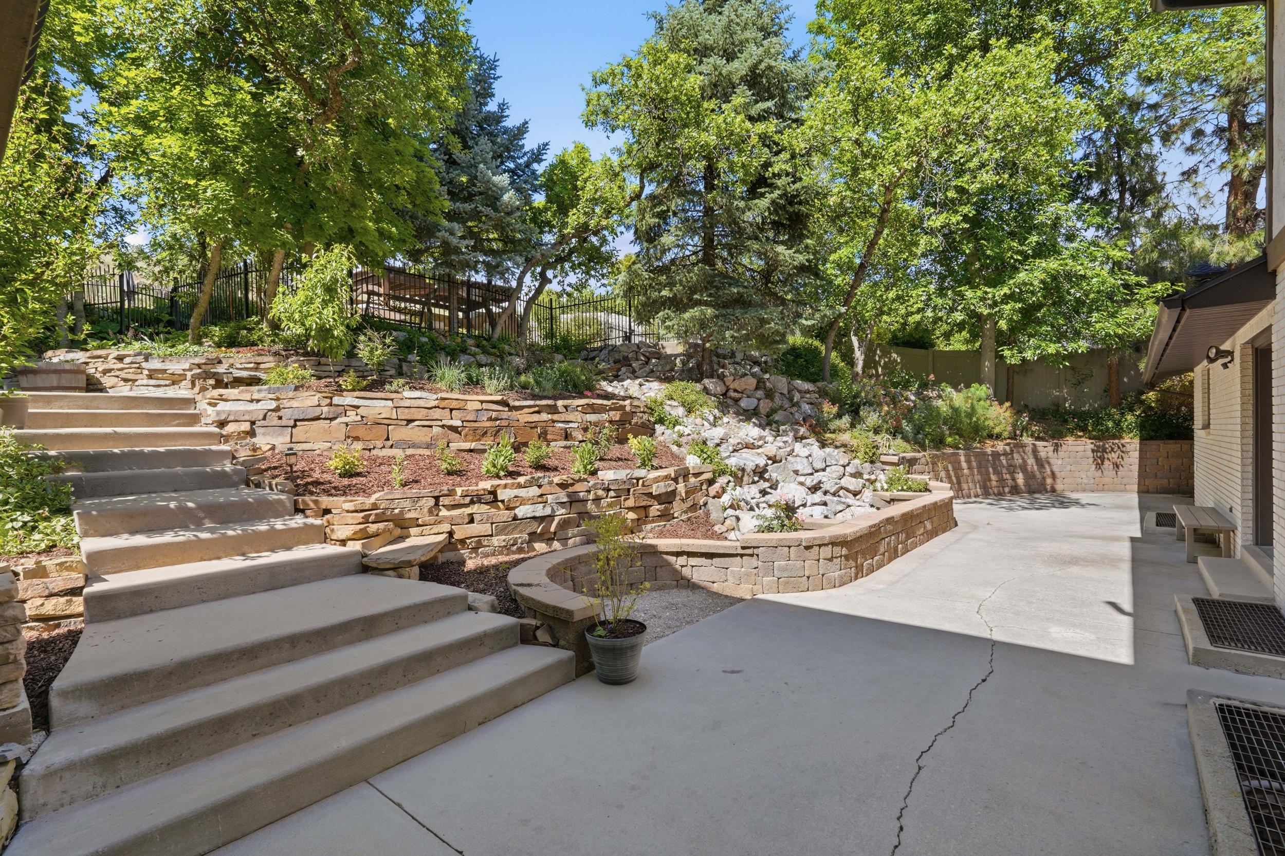 Tiered landscaping with natural stone retaining walls and mature trees