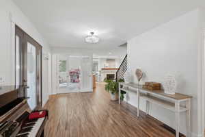 Spacious entryway featuring wood-finish flooring, a contemporary chandelier, white walls, and a console table