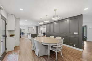 Dining area with wood-finish flooring, featuring a decorative paneled accent wall