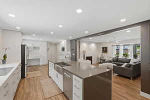 Open concept kitchen featuring a large island with a farmhouse sink, stainless steel dishwasher, and ample counter space