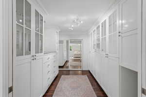 Custom white cabinetry with glass-front uppers, built-in drawers, and dark wood-finish flooring