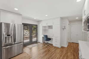 Bright kitchen area featuring wood-finish flooring, white cabinetry, and recessed lighting