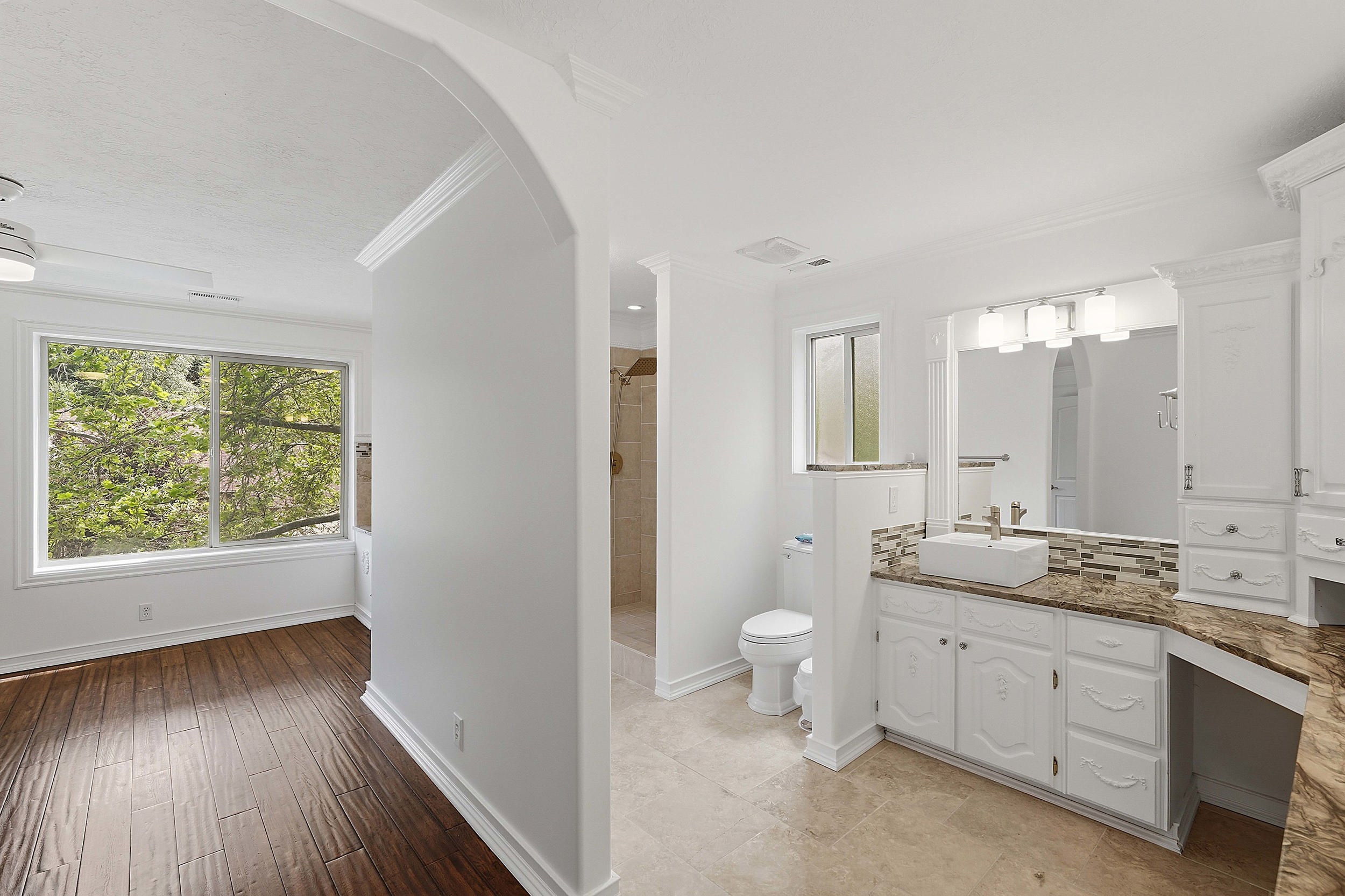 Spacious bathroom featuring a vessel sink, an expansive vanity with storage, a large mirror, and tiled flooring