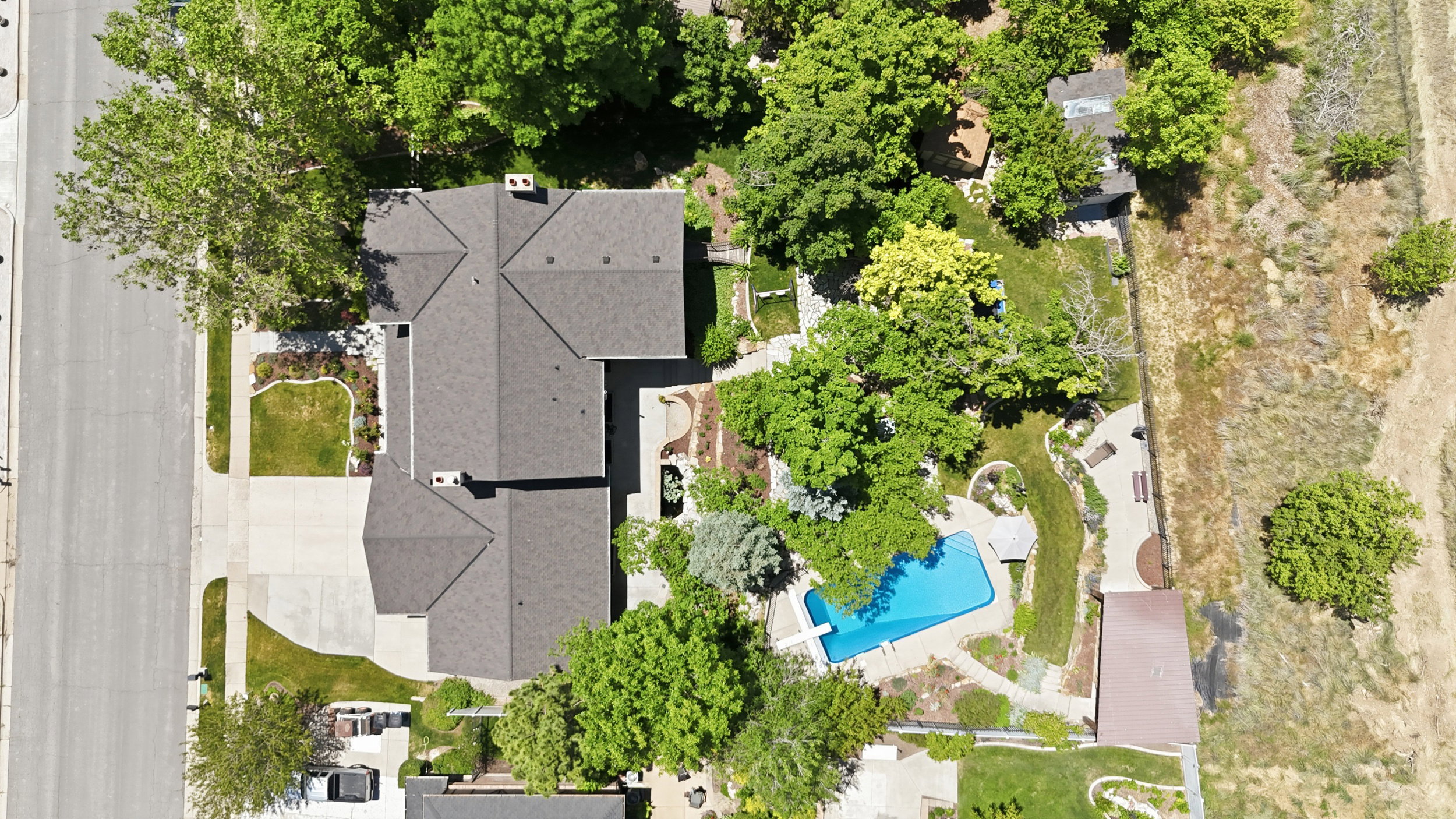 Expansive property featuring a multi-gabled main residence with a dark shingle roof, a spacious driveway, and mature landscaping