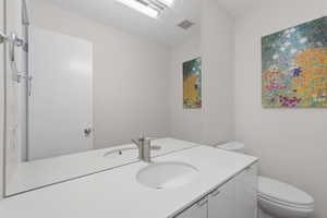 Contemporary vanity featuring a white countertop with integrated sinks, brushed nickel faucets, and sleek white cabinetry