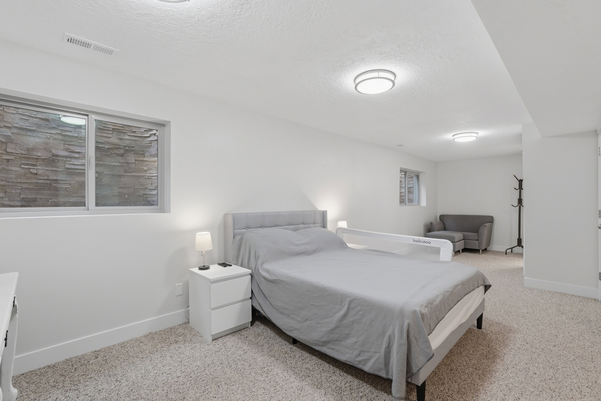Carpeted room featuring a window with a stone-clad exterior wall, recessed lighting, and a neutral color palette