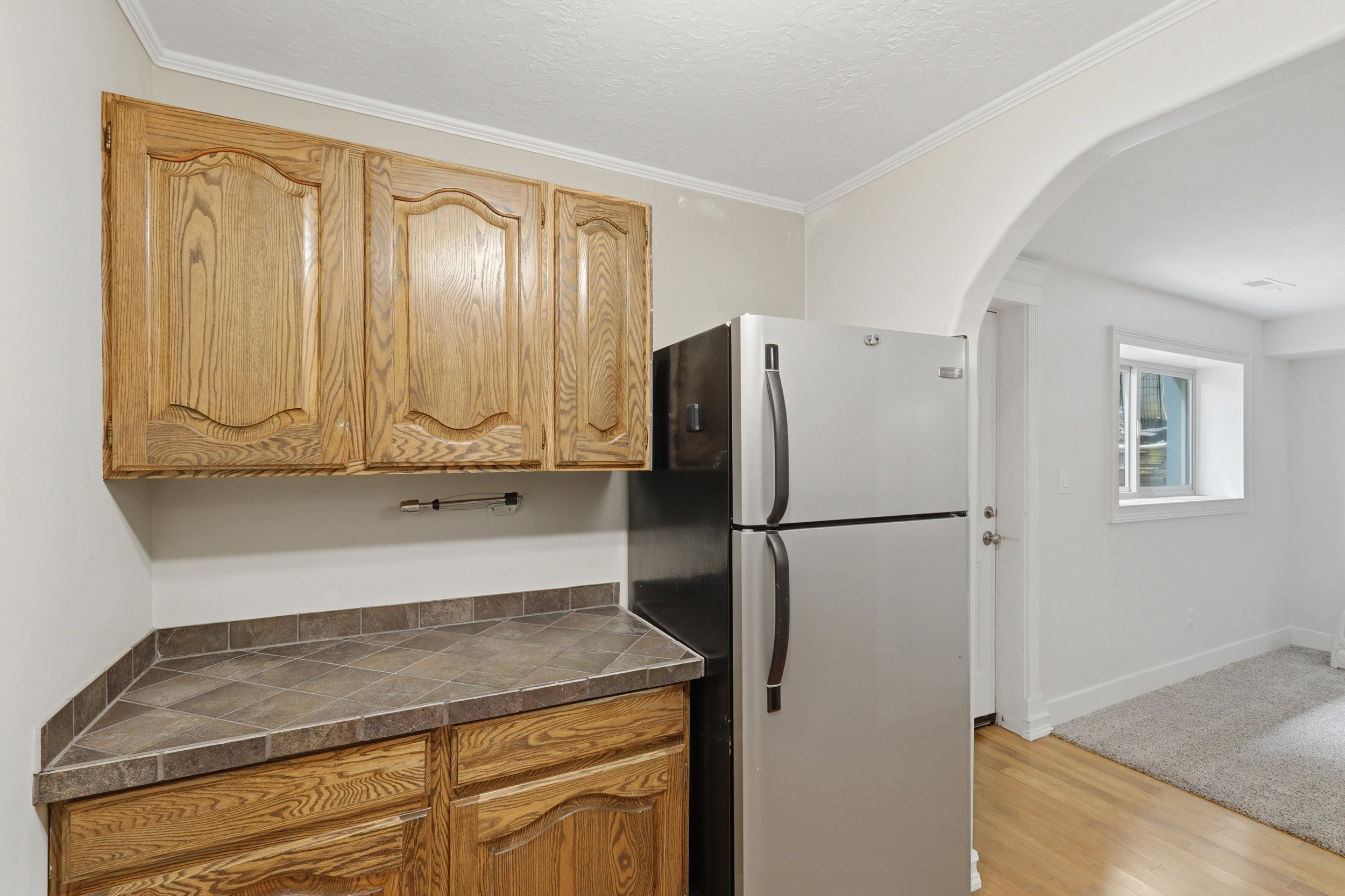 Kitchenette featuring oak cabinetry, tile countertop, and a stainless steel refrigerator