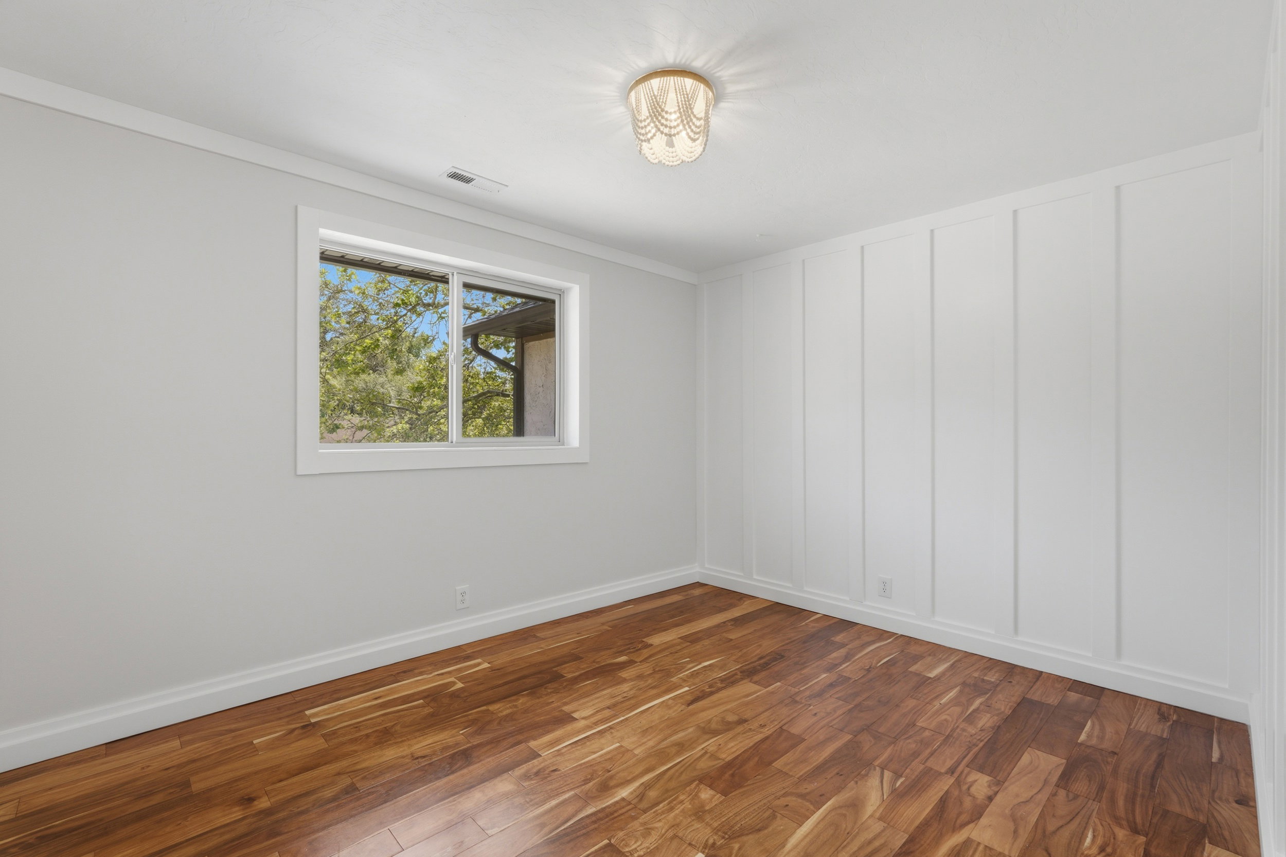 Warm wood-finish flooring complements the crisp white board and batten accent wall
