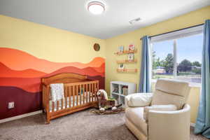 Bedroom featuring a striking multi-toned accent wall, carpeted flooring, and a large window with light blue drapes