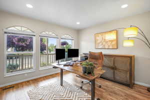 Dedicated office space featuring wood-finish flooring, recessed lighting, and three arched windows