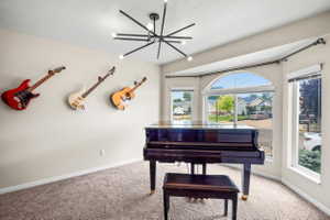 Bay window with arched transom window, modern sputnik chandelier, light beige walls, and  carpet flooring