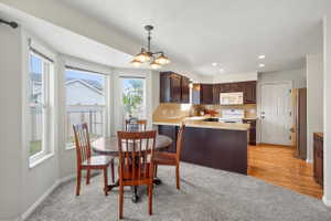 Kitchen and dining area featuring dark wood cabinetry, light countertops, integrated and stainless appliances, and a peninsula with breakfast bar seating