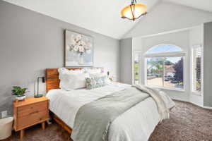 Primary Bedroom Vaulted ceilings with a semi-flush mount light fixture, bay window with an arched transom, horizontal blinds, and textured gray walls