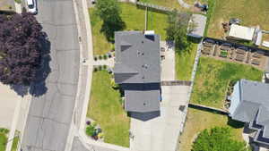 Residential property featuring an asphalt shingle roof, concrete driveway, and established green lawns