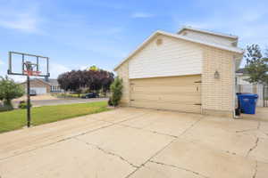 Exterior featuring a two-car garage with a light-colored door, white vinyl siding, and light brick accents