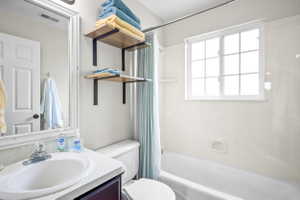 Bright bathroom featuring a window above the tub, a vanity with an integrated sink, and white walls