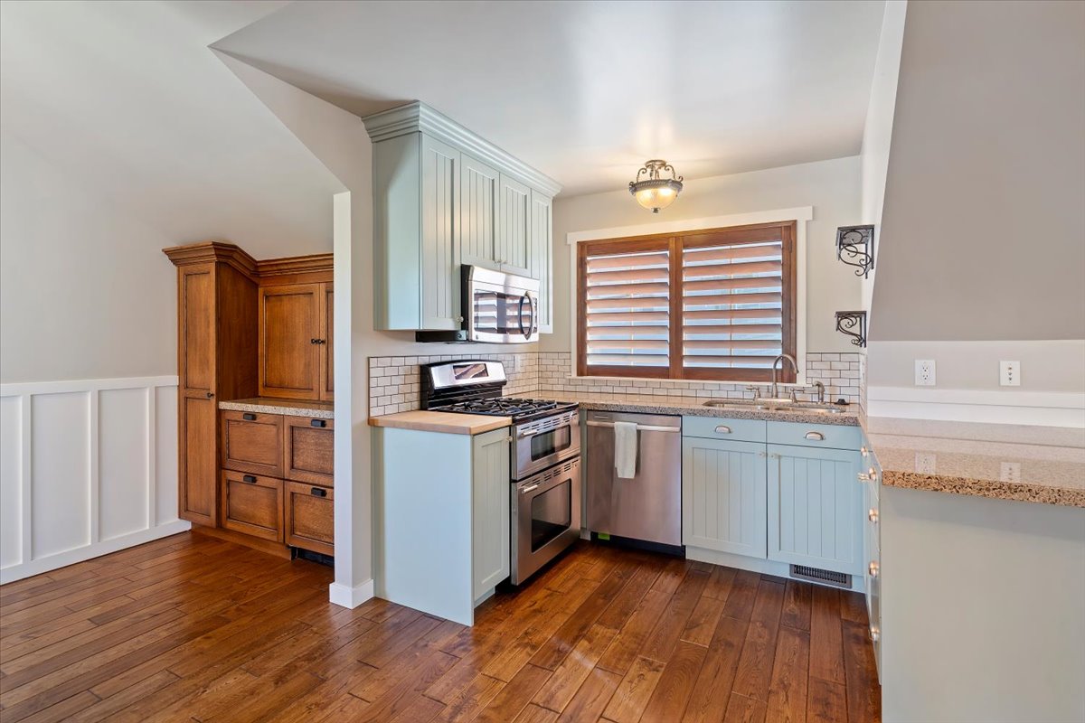 Kitchen featuring light blue cabinetry, stainless steel appliances, and wood-finish flooring