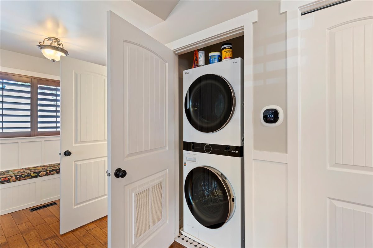 Laundry closet with stacked appliances and a white paneled door