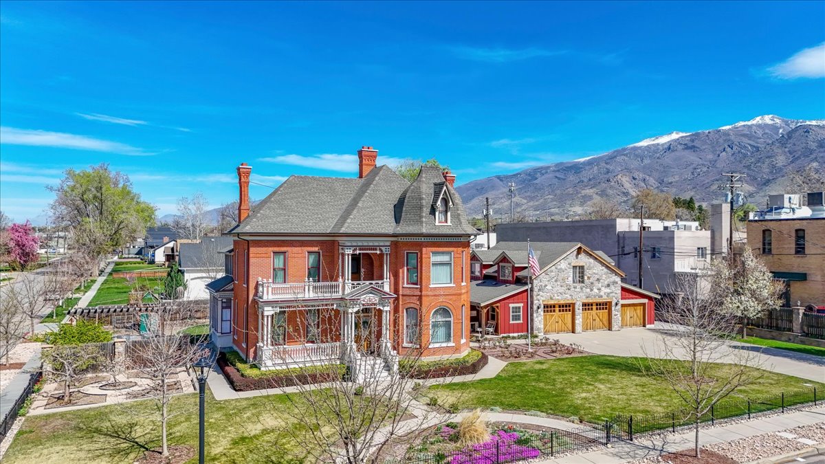 Victorian-style brick residence featuring a multi-gabled roof, decorative chimneys, and a covered porch with white columns