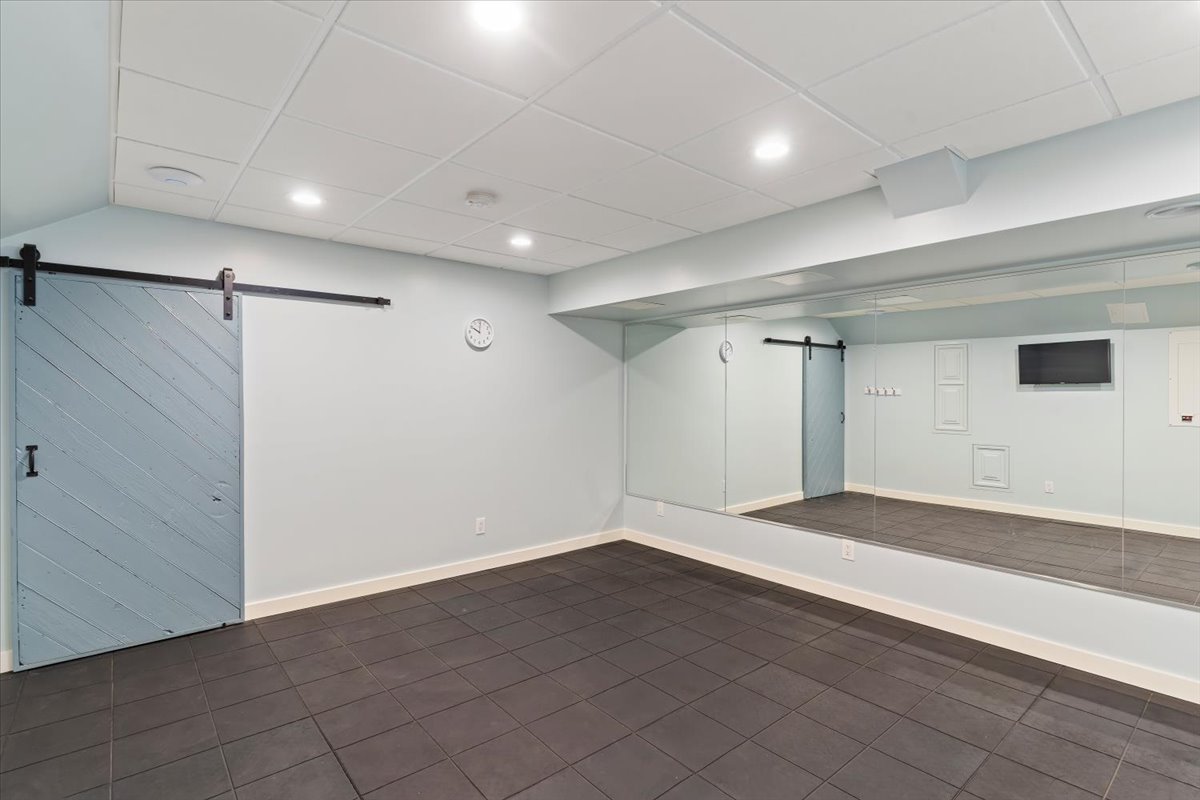 Spacious room featuring dark tile flooring, a full-wall mirror, and a light blue barn door