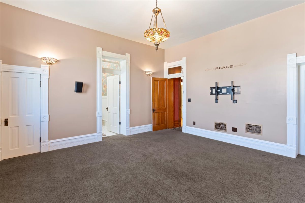 Spacious room featuring neutral carpeting, decorative wall sconces, and a Tiffany-style pendant light