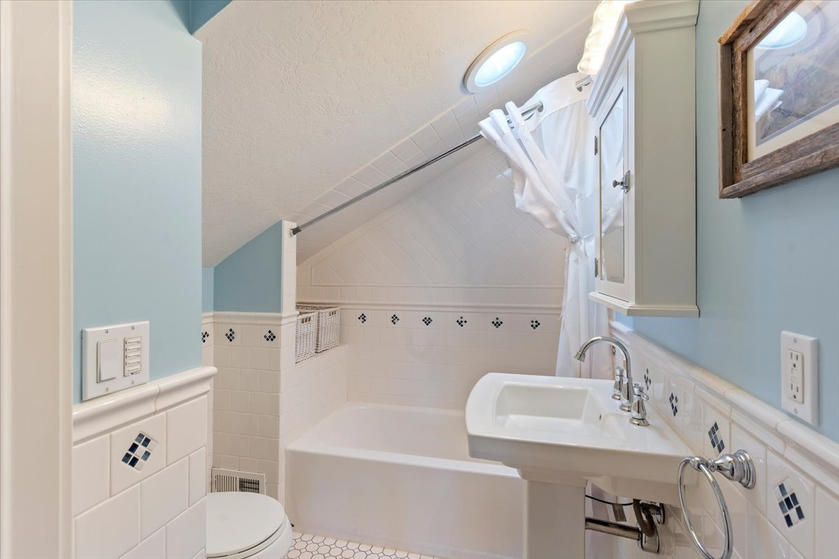 Bathroom featuring a pedestal sink, built-in bathtub, and a wall-mounted medicine cabinet