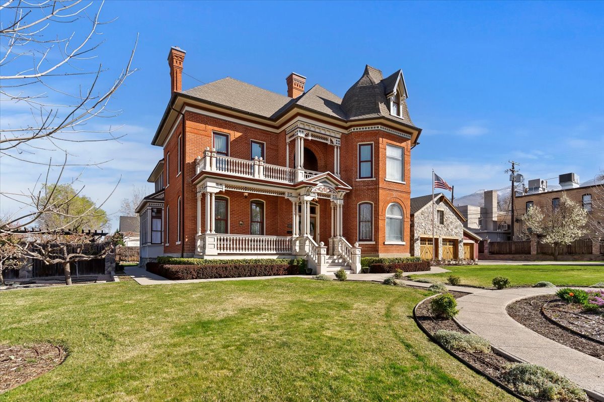 Brick residence featuring a prominent turret, columned porch, and second-story balcony with white balustrades
